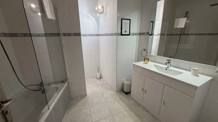 Salle de bain avec baignoire et lavabo au Grand Hôtel Molière.