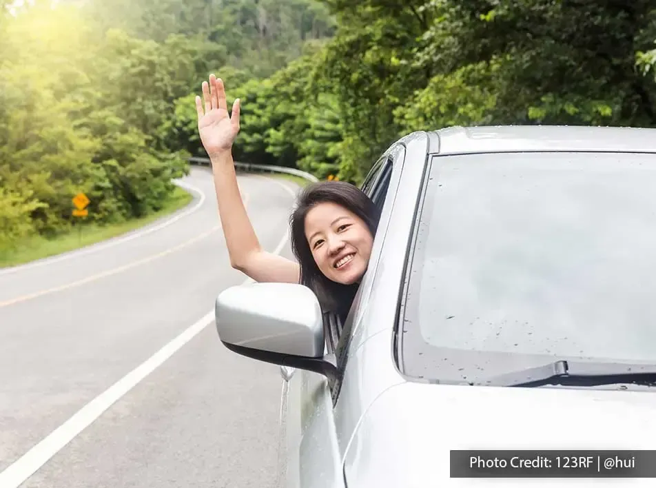 A woman was raising her hand through the car window during her road trip - Lexis Suites Penang