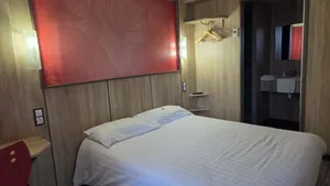 Chambre avec lit double et salle de bain à l'Hôtel Aurillac Aéroport.