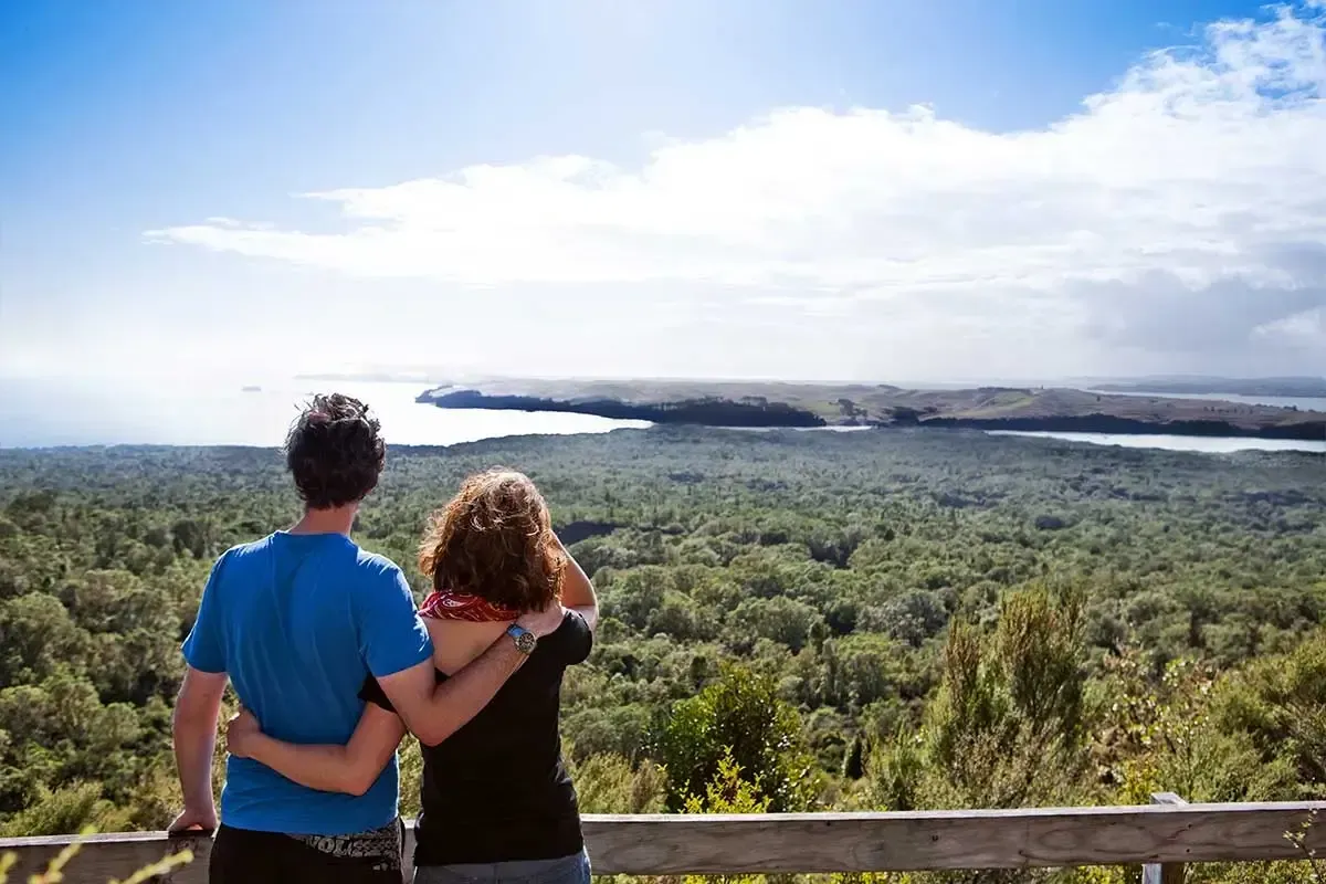 Visitors standing above Rangitoto Island’s Hauraki Gulf