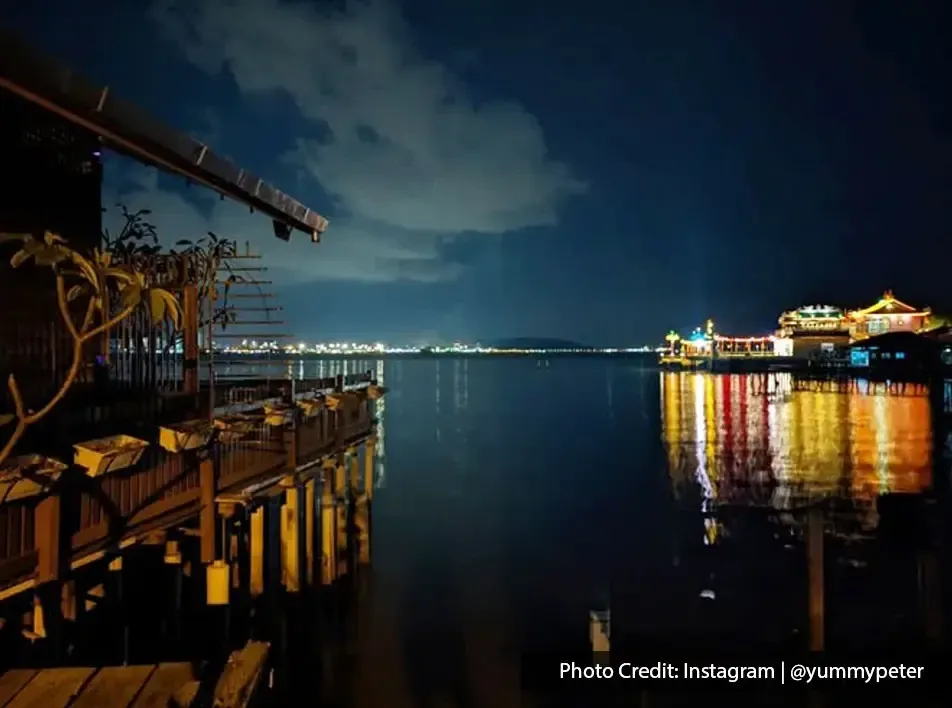 Nightscape of Clan Jetty with calm sea and glowing lights across the water.