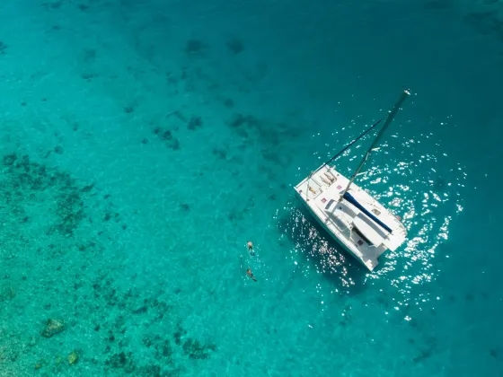 Aerial view of a catamaran and two people swimming in the stunning turquoise ocean near Saint Martin Beach Resort & Spa