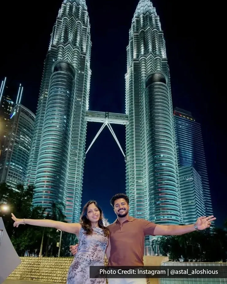 Couple posing in front of the Petronas Twin Towers at night