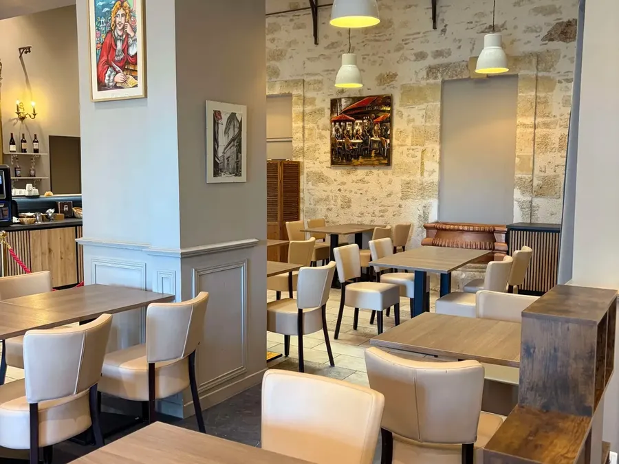 Intérieur élégant d'un restaurant avec tables en bois et chaises blanches au Grand Hôtel Molière.