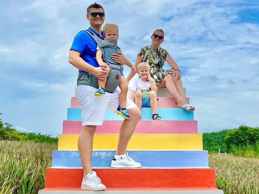 A family of four sits together on vibrant, colourful steps at Sky Ladder Pineapple Farm - Lexis Port Dickson 