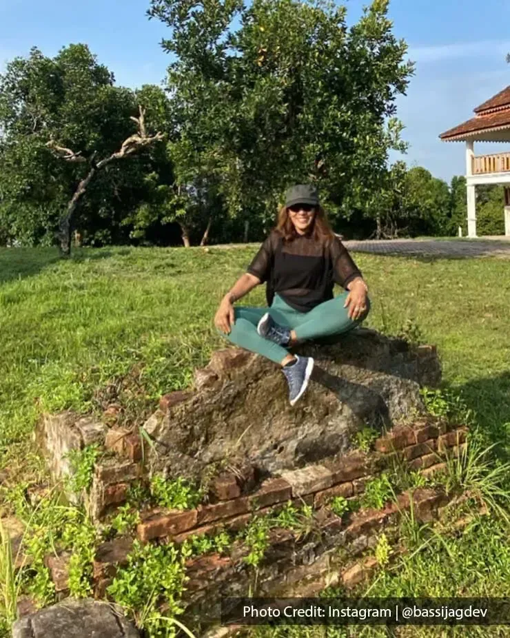 A lady sitting on stone ruins at Lukut Fort and Museum, surrounded by lush grass - Grand Lexis Port Dickson