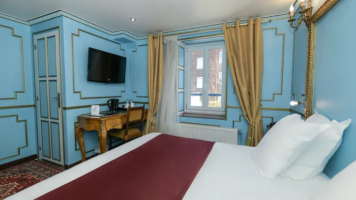 Chambre élégante avec lit, bureau, télévision et fenêtre chez Hôtel Villa Aultia.