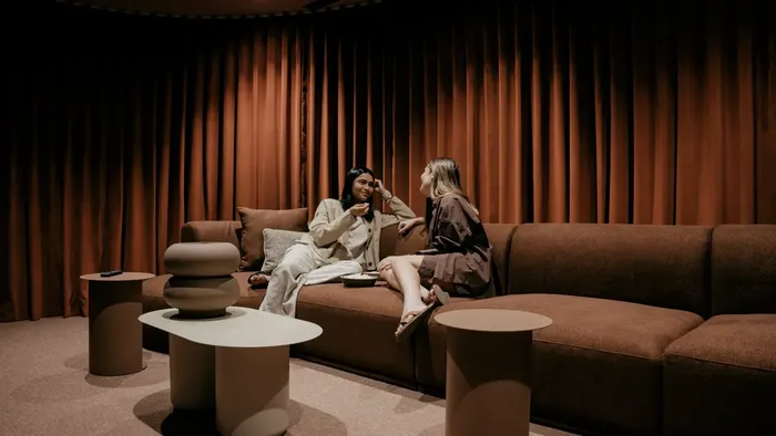 Two women relaxing on a couch in a cozy cinema lounge at Caulfield Place, Caulfield North.