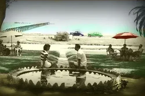 Classic imagery of a couple seated by a stone pond overlooking the coastal pier near The White House Hotel