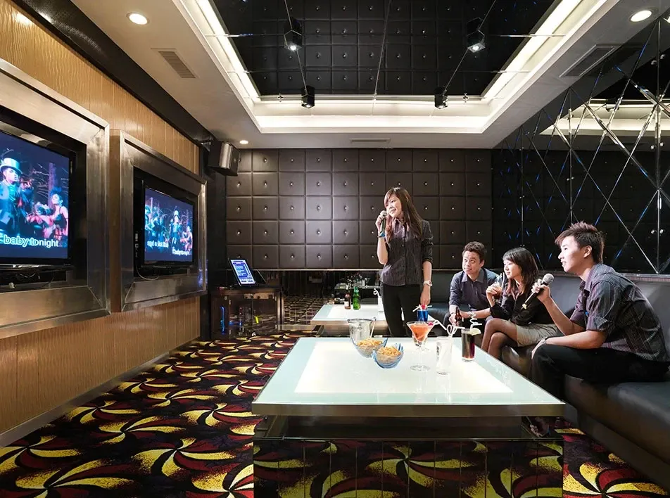 Group singing karaoke together in private room.