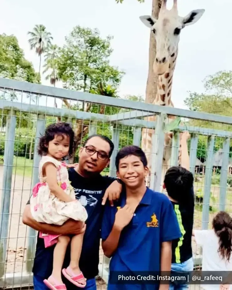 A family were taking a picture with a giraffe at Zoo Taiping - Lexis Suites Penang