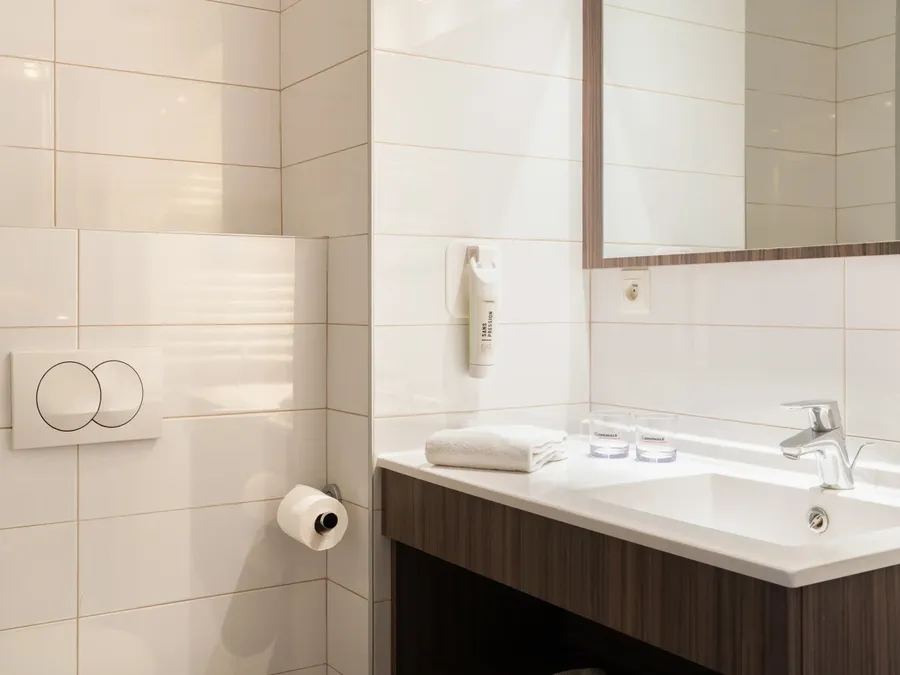 Modern bathroom with a toilet and sink in the Triple Studio at Appart’Hôtel Hévéa, Valence.
