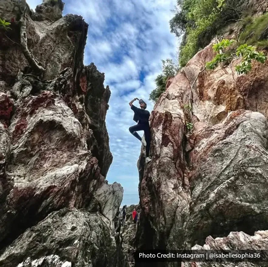 Individu berdiri di celah batu besar sambil bergaya di hadapan langit cerah - Lexis Hibiscus Port Dickson