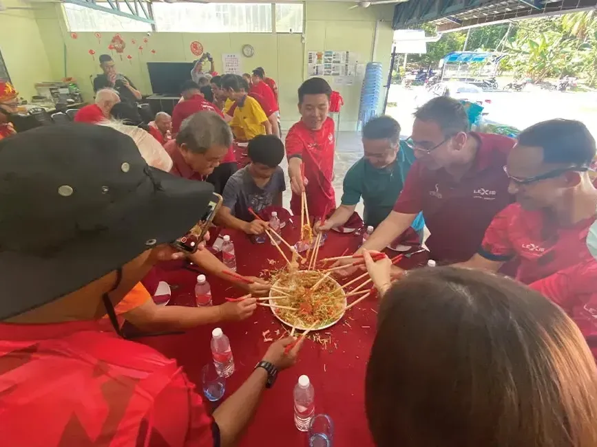 A group of people tossing yee sang together during Chinese New Year - Lexis Hotels & Resorts