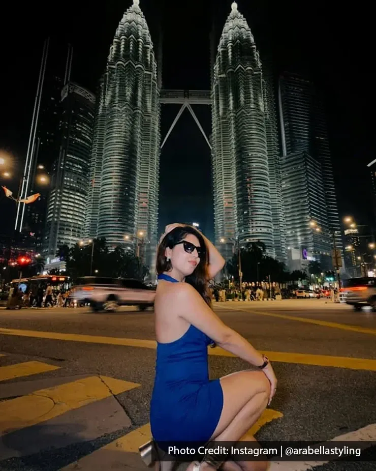 Woman posing in front of the Petronas Twin Towers at night