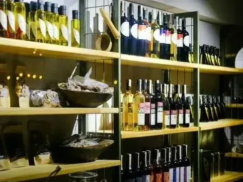 Wooden shelves stocked with various wine bottles and artisanal food products in a specialty store