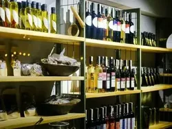 Wooden shelves stocked with various wine bottles and artisanal food products in a specialty store