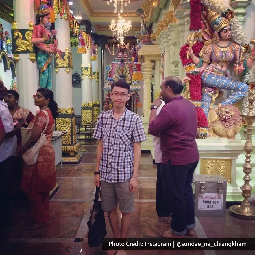Man standing inside Sri Mahamariamman Temple with colorful Hindu statues in Penang.