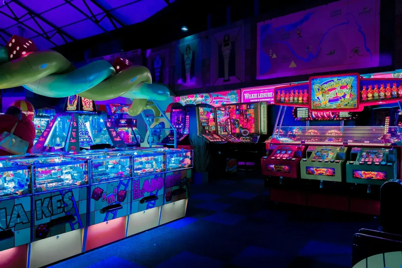 A neon-lit arcade hall lined with game machines