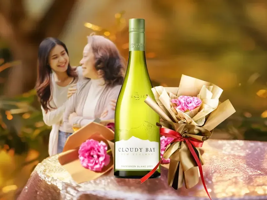 Two women standing and smiling together next to a bottle of wine - Imperial Lexis Kuala Lumpur