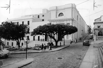 Black and white image of El Convento building with people and cars on a cobblestone street.