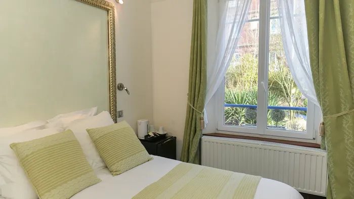 Chambre confortable avec lit, radiateur, et vue sur jardin à Hôtel Villa Aultia.