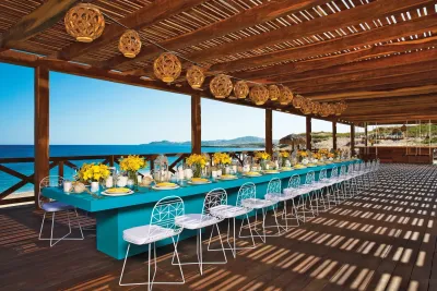 Table à manger élégante au Saint Martin Beach Resort & Spa, avec des fleurs jaunes, une longue table sarcelle et une vue sur l'océan.