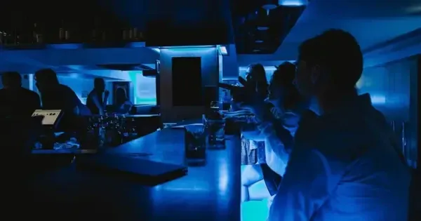 Patrons sitting inside at neon blue bar