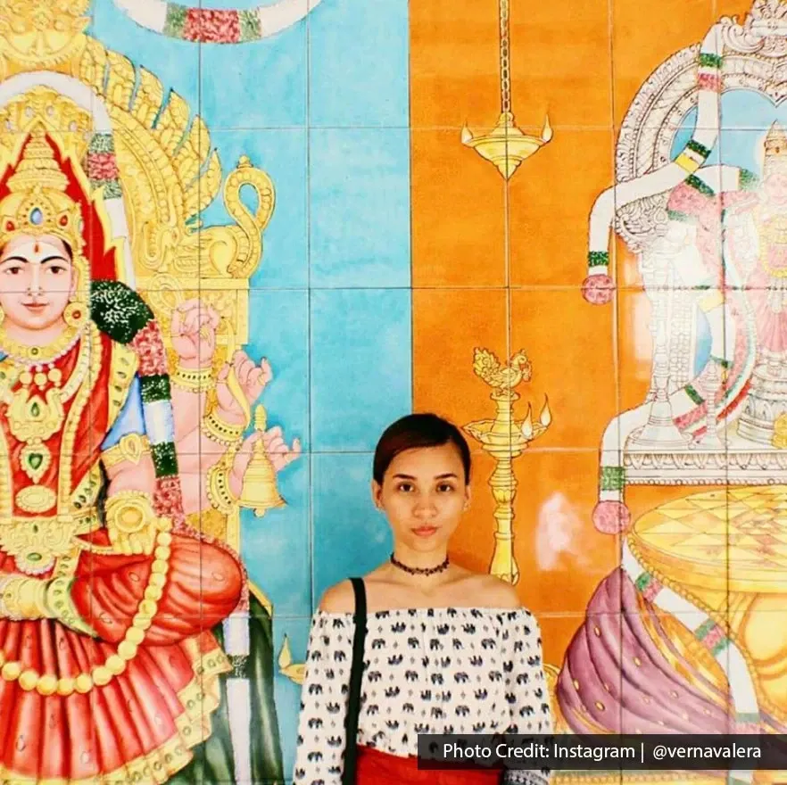 Visitor posing in front of vibrant Hindu goddess wall art at Sri Mahamariamman Temple Penang.